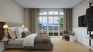 Un dormitorio con una cama grande, una silla, un televisor y vista a un cuerpo de agua.