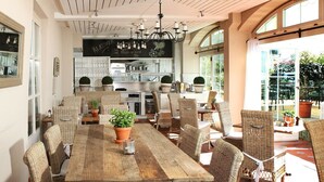 Un comedor con mobiliario de mimbre, una mesa de madera y plantas en macetas.