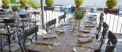 A dining table set for six with chairs, a vase with greenery, and a view of the lake and mountains.