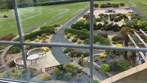 Vista de un jardín ajardinado con un patio, césped y una lejana vista del paisaje rural.