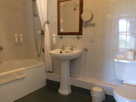 Un baño con bañera, lavamanos pedestal, inodoro y espejo.
