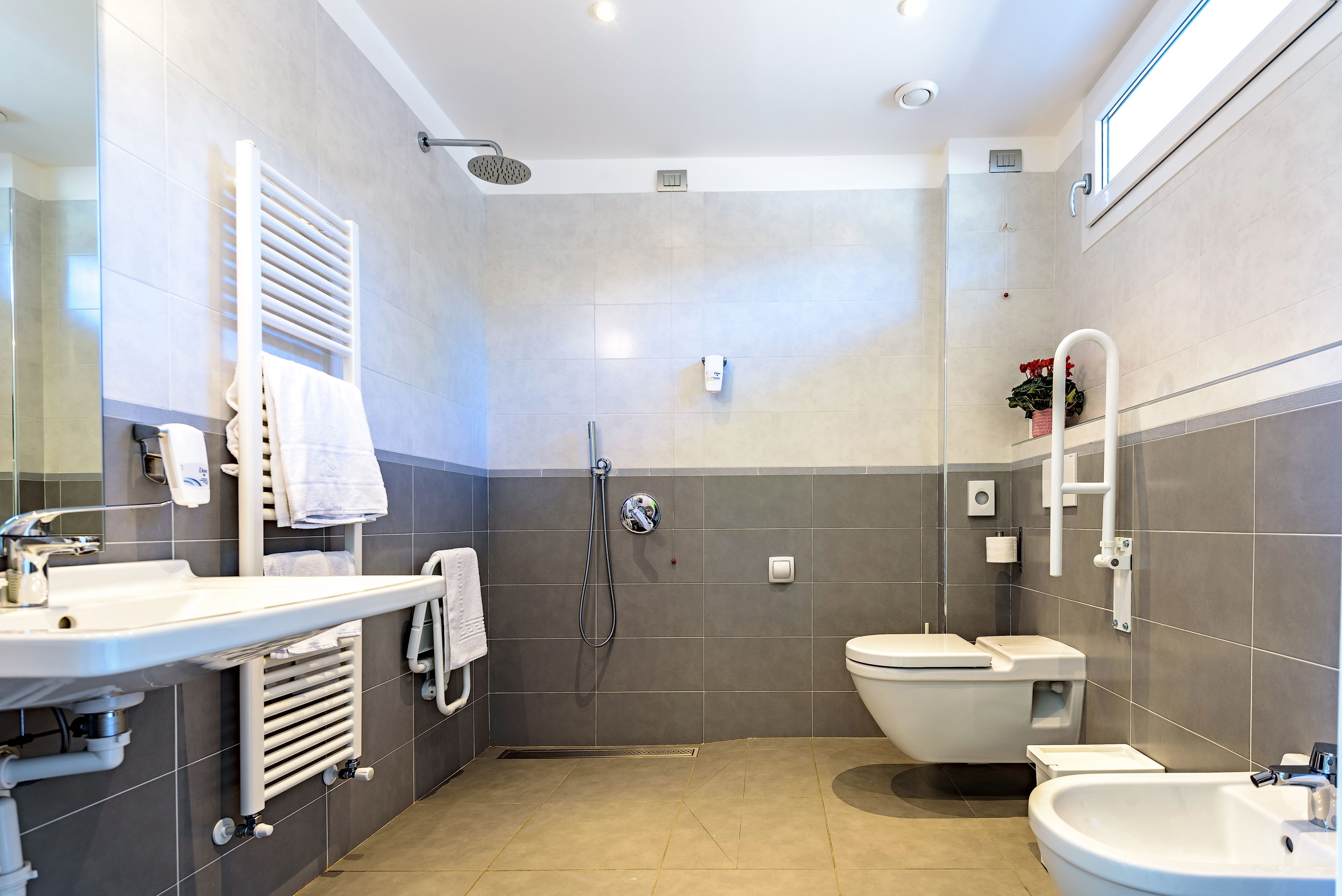 A modern bathroom with a shower, toilet, sink, and bidet.
