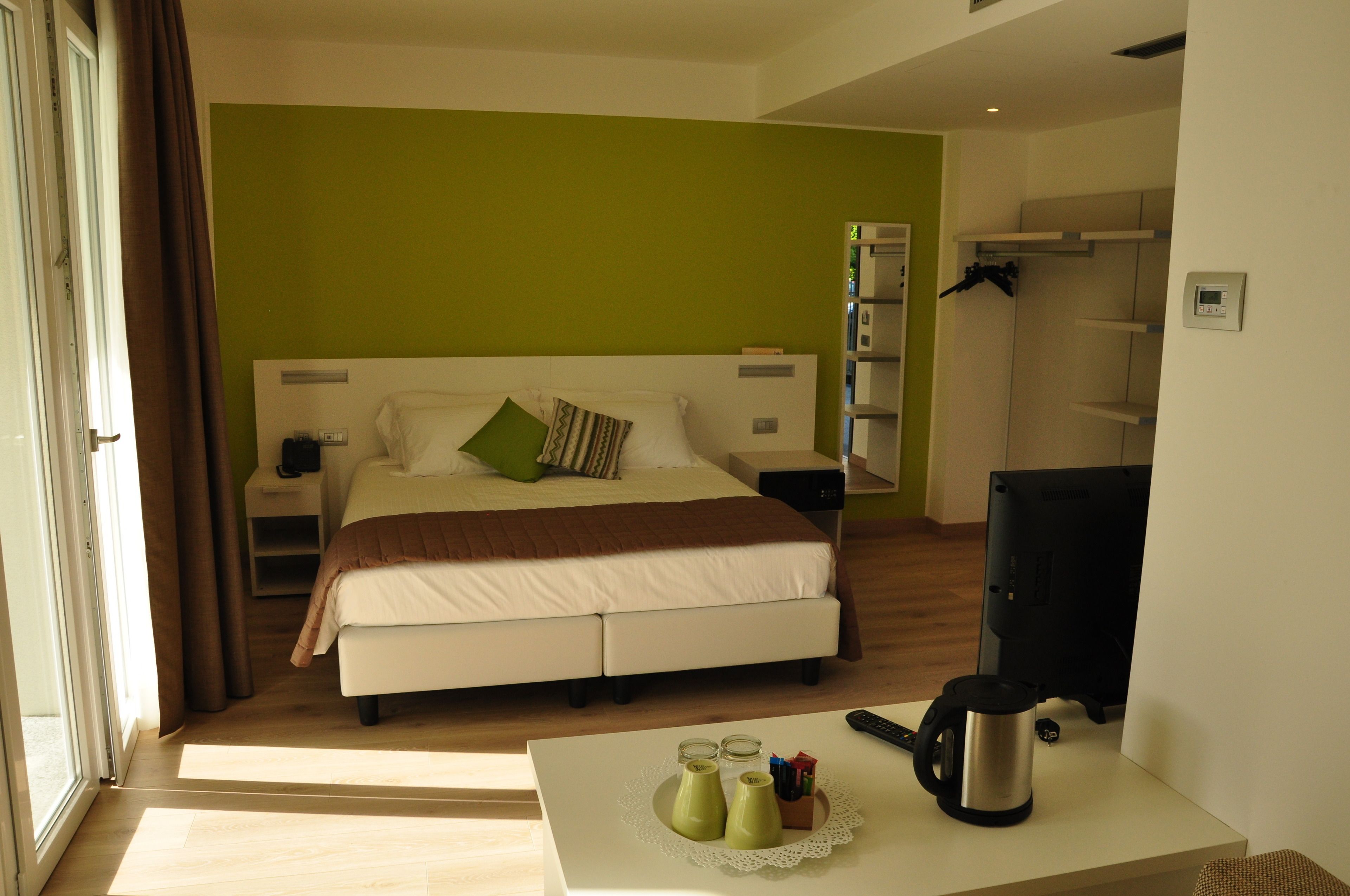 A hotel room with a double bed, a desk with a kettle, and a television.
