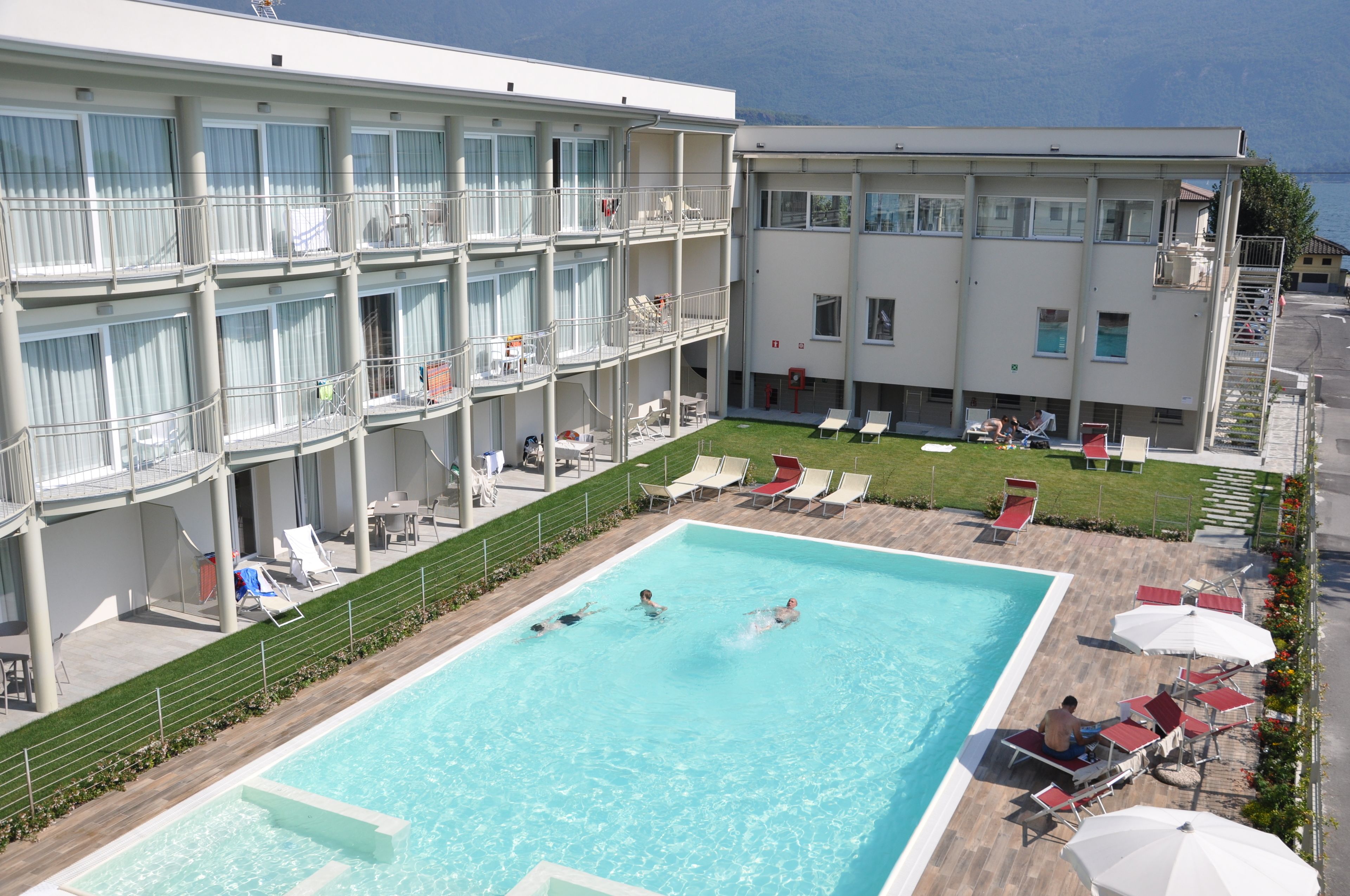 A hotel with a swimming pool, multiple balconies, and outdoor seating areas.