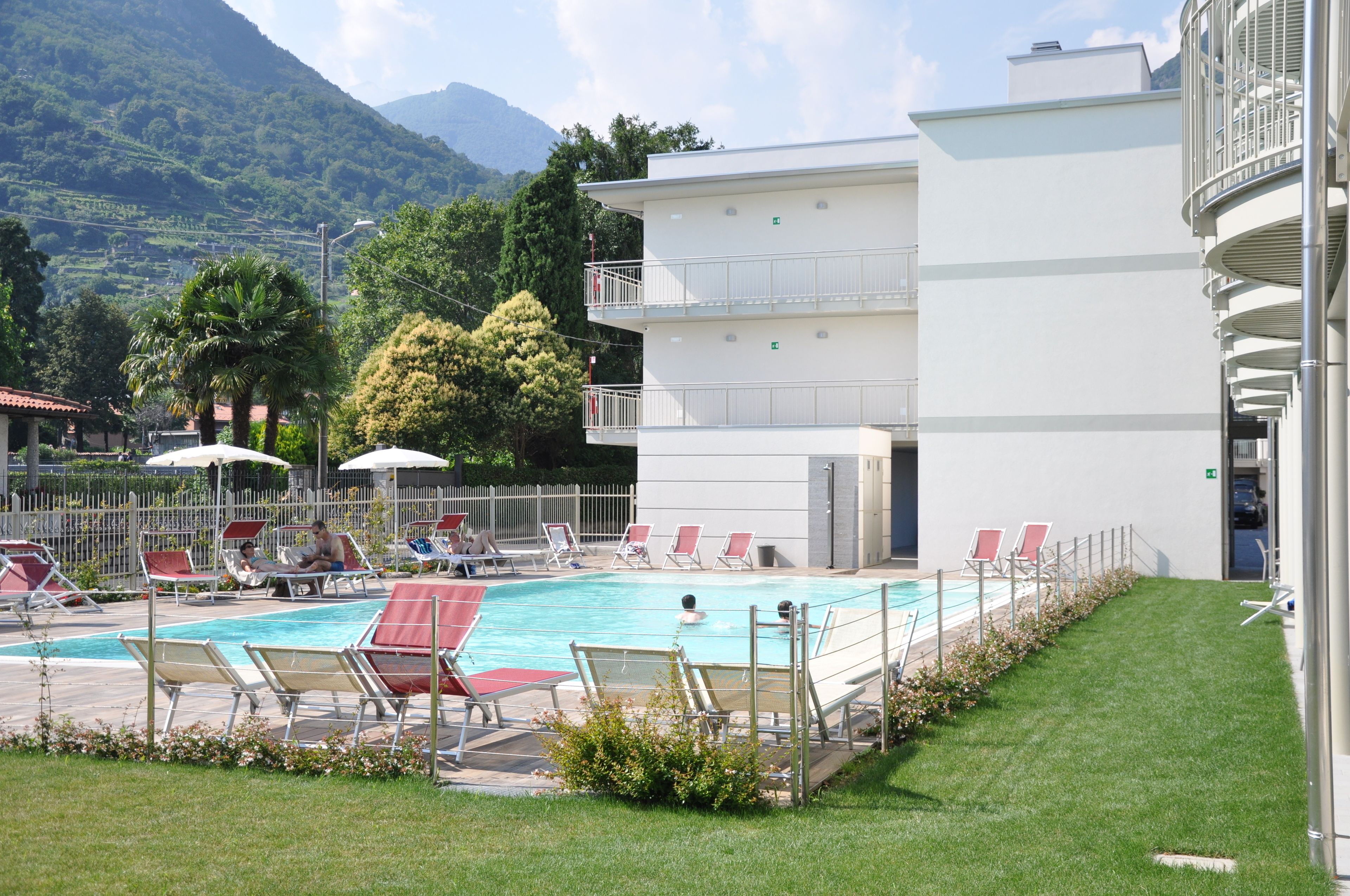 Un espace piscine avec des chaises longues et un bâtiment doté d’un balcon.