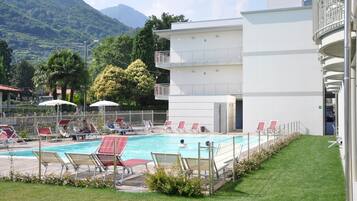 Un espace piscine avec des chaises longues et un bâtiment doté d’un balcon.