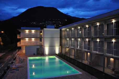 Una piscina al aire libre, sombrillas, sillones reclinables de piscina