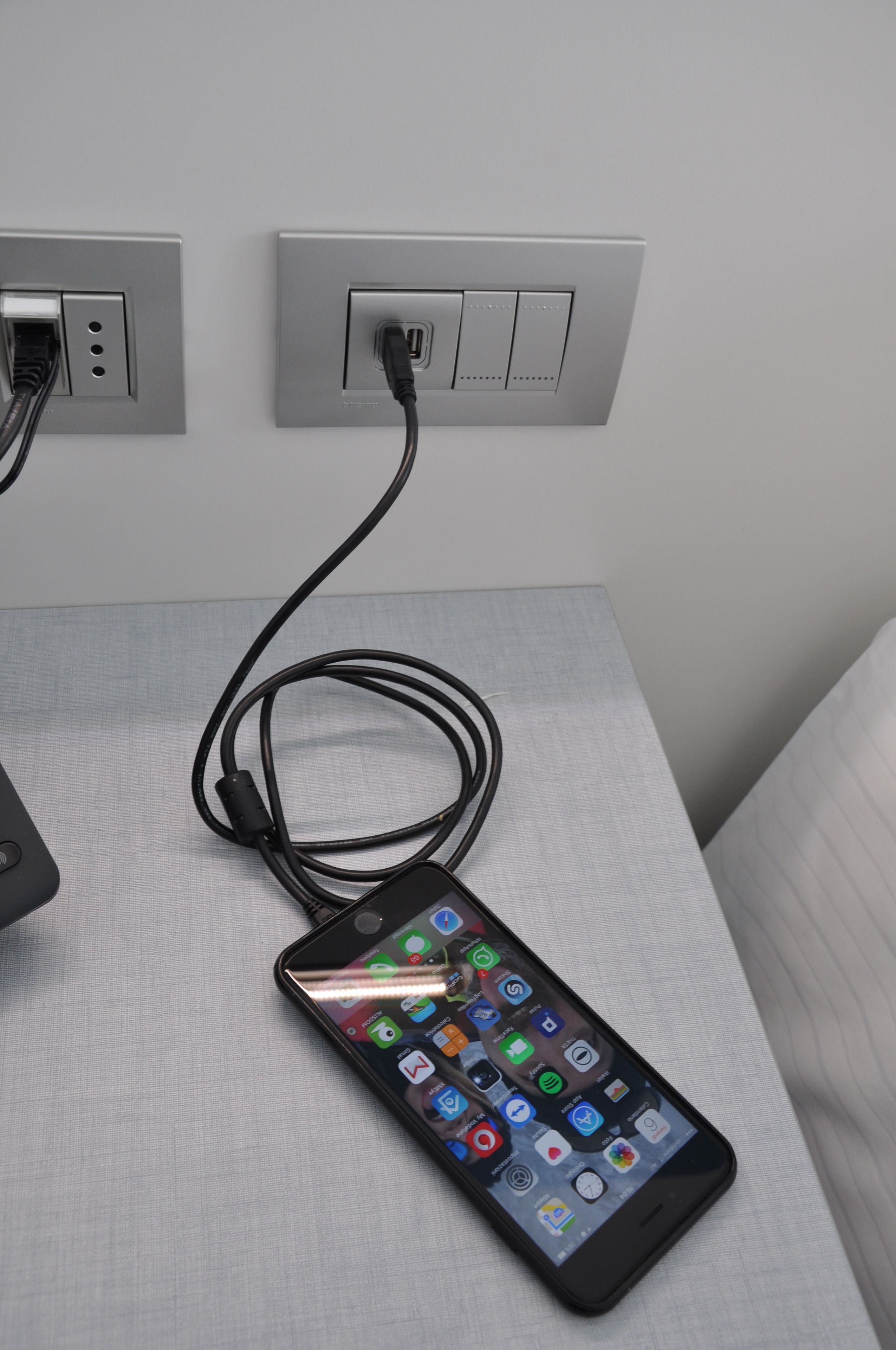 A smartphone charging on a table with a power outlet.