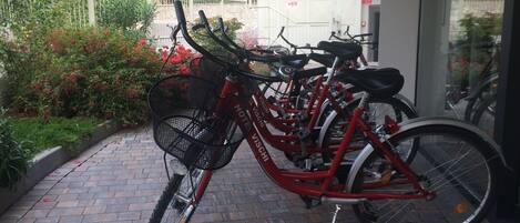 A red bicycle with a basket, parked on a brick pathway.