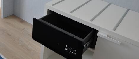 A modern room with a built-in TV on a white shelf, a white cabinet with a black drawer, and a wooden floor.
