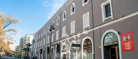 Un edificio con varias fachadas comerciales, que incluye un albergue juvenil y un bar llamado 'Faller'.