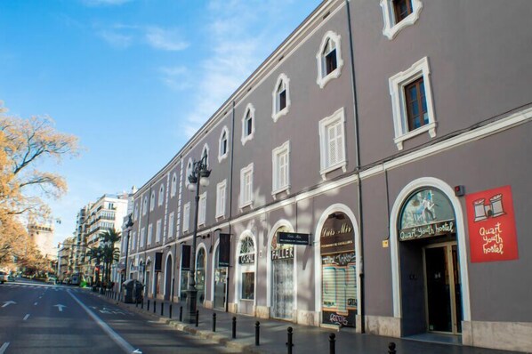 A building with multiple storefronts, including a youth hostel and a bar named 'Faller'.