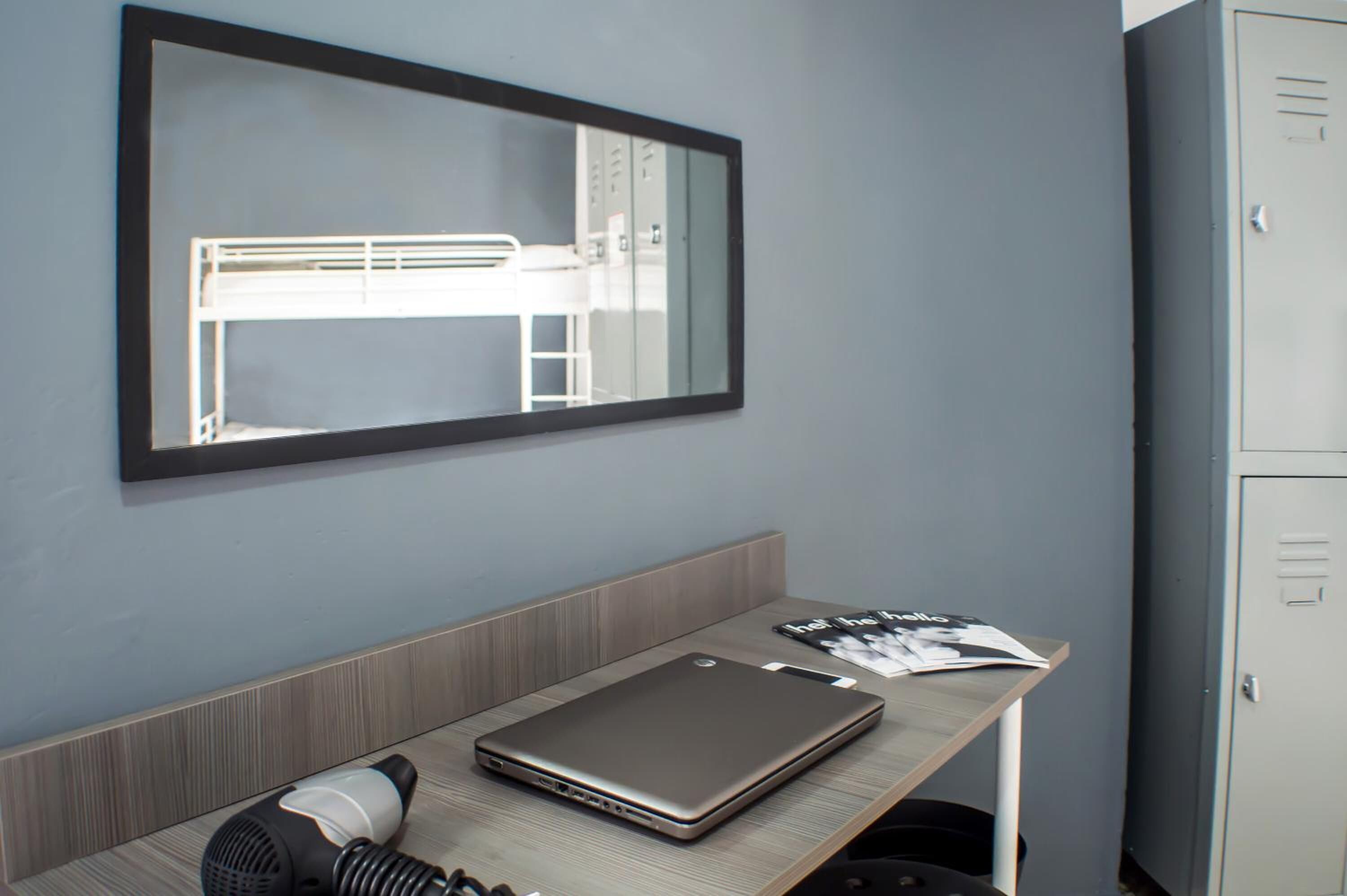 Une chambre avec un lit superposé, un bureau avec un ordinateur portable, un sèche-cheveux et un magazine.