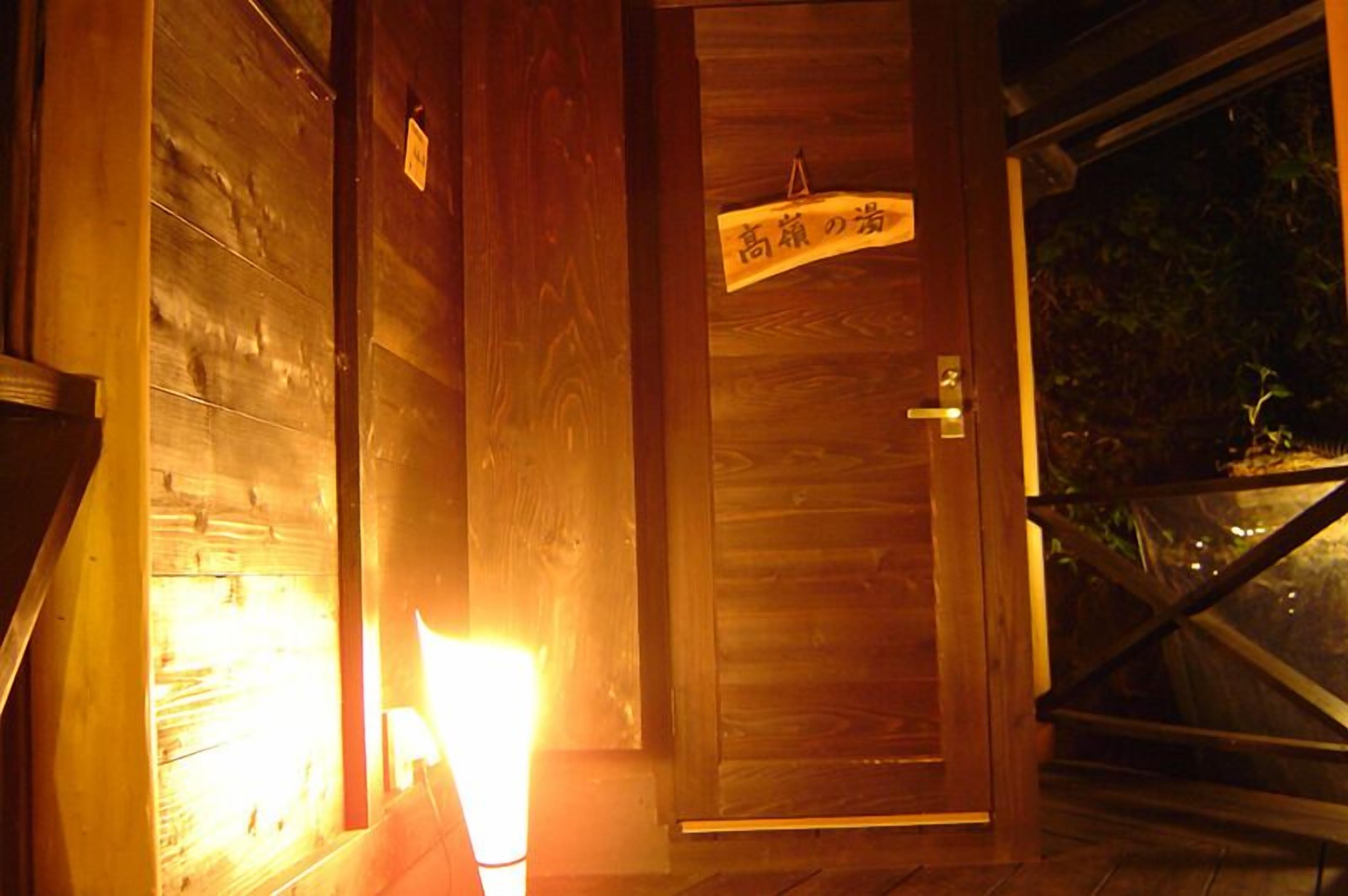 Une porte en bois avec une enseigne au-dessus, une fenêtre donnant sur la verdure et une balustrade en bois.