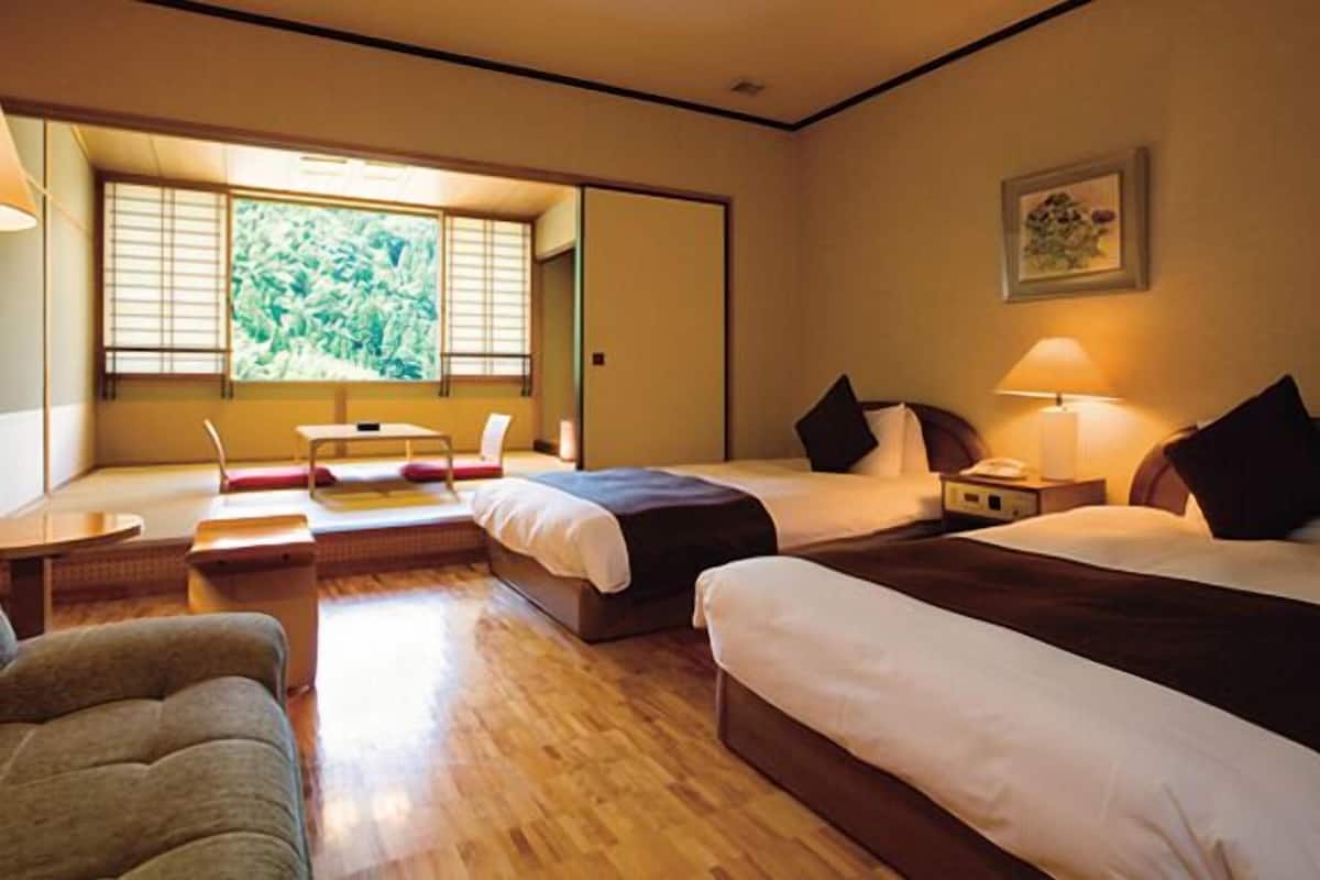 A hotel room with two beds, a sofa, a small table, and a TV.