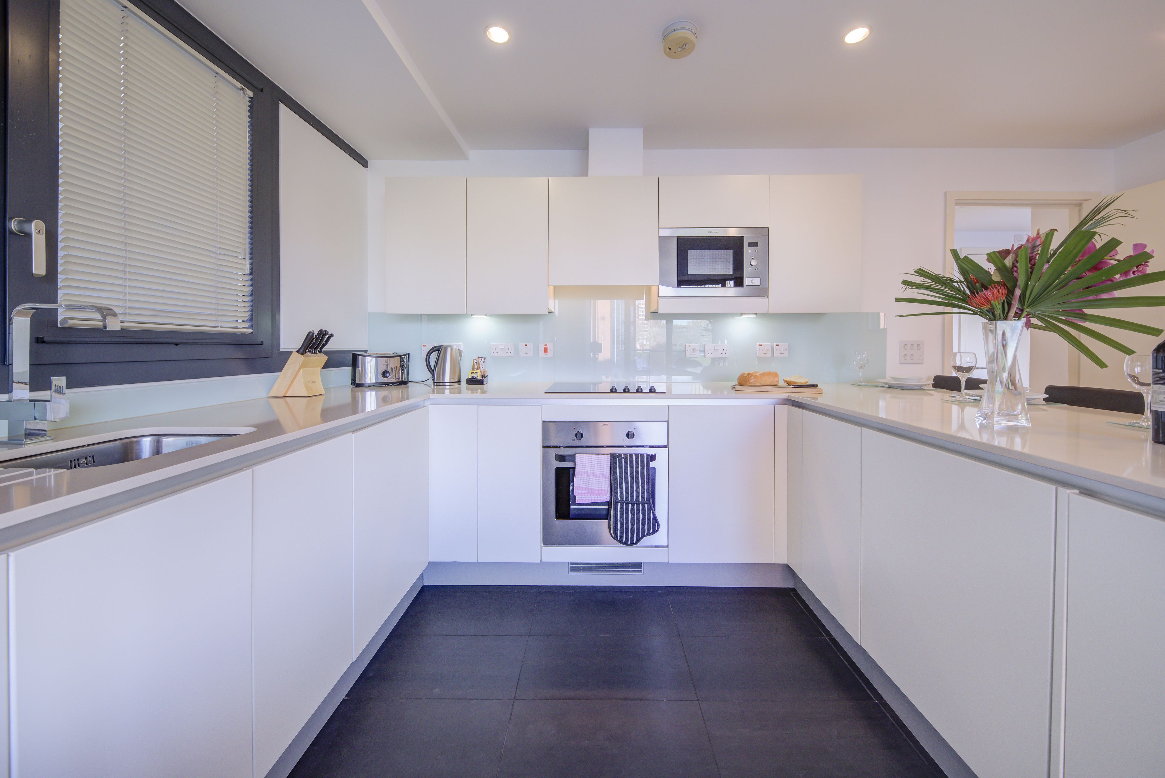 Una cucina moderna con mobili bianchi, forno integrato e microonde.