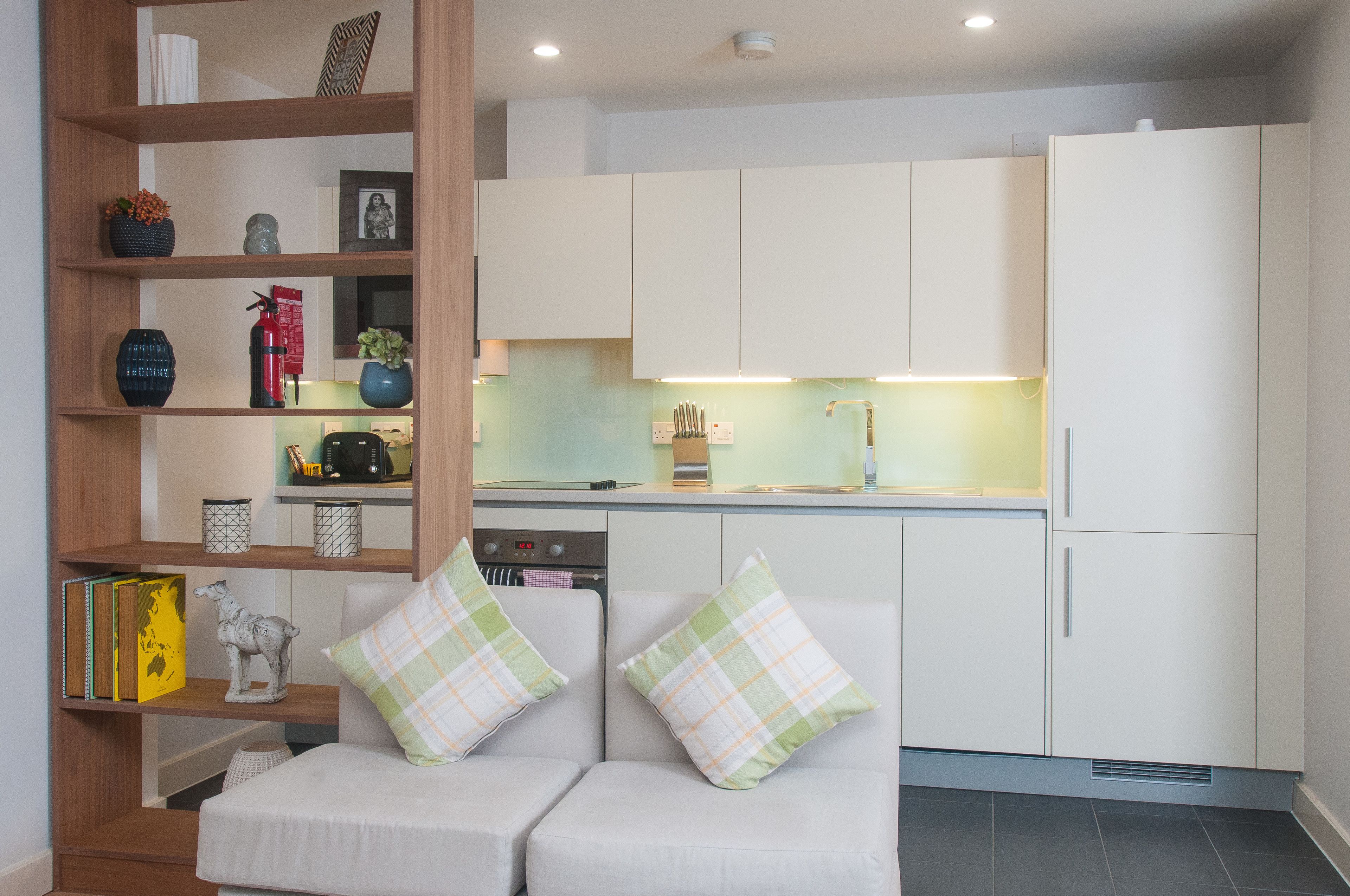A compact kitchen with white cabinets, a built-in oven, and a dining area with a white table and chairs.