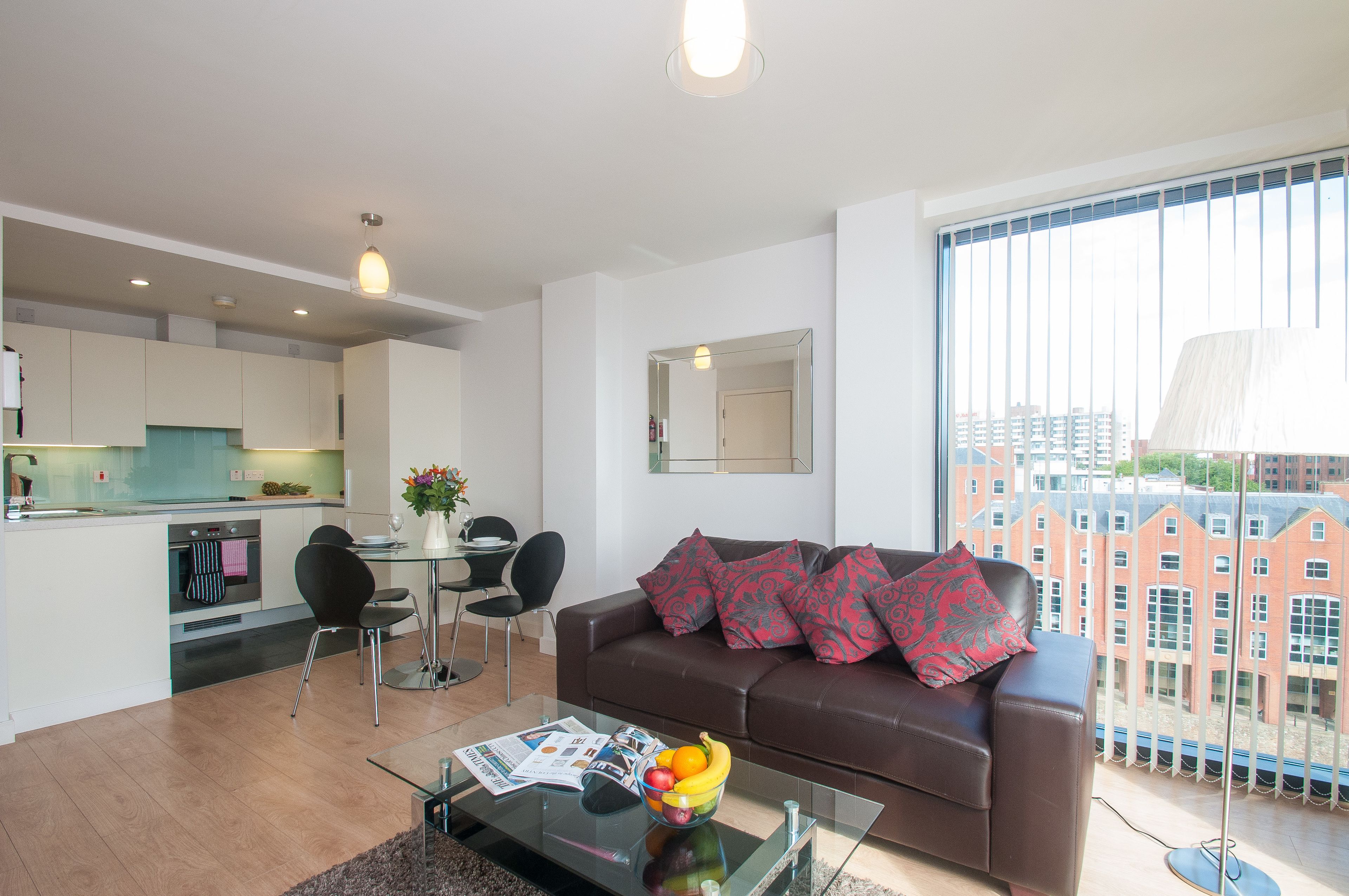 Een modern appartement met keuken, eethoek en woonkamer met groot raam.