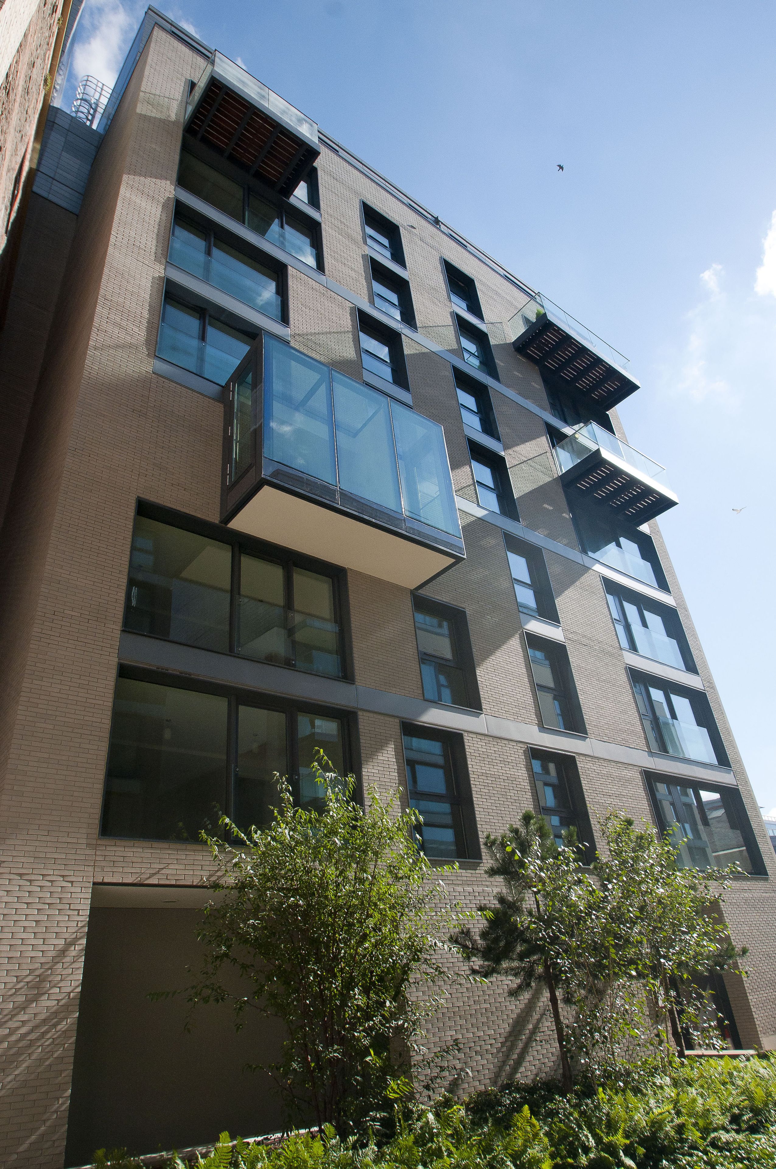 Ein mehrgeschossiges Gebäude mit modernem architektonischen Design, das große Fenster und Balkone aufweist.