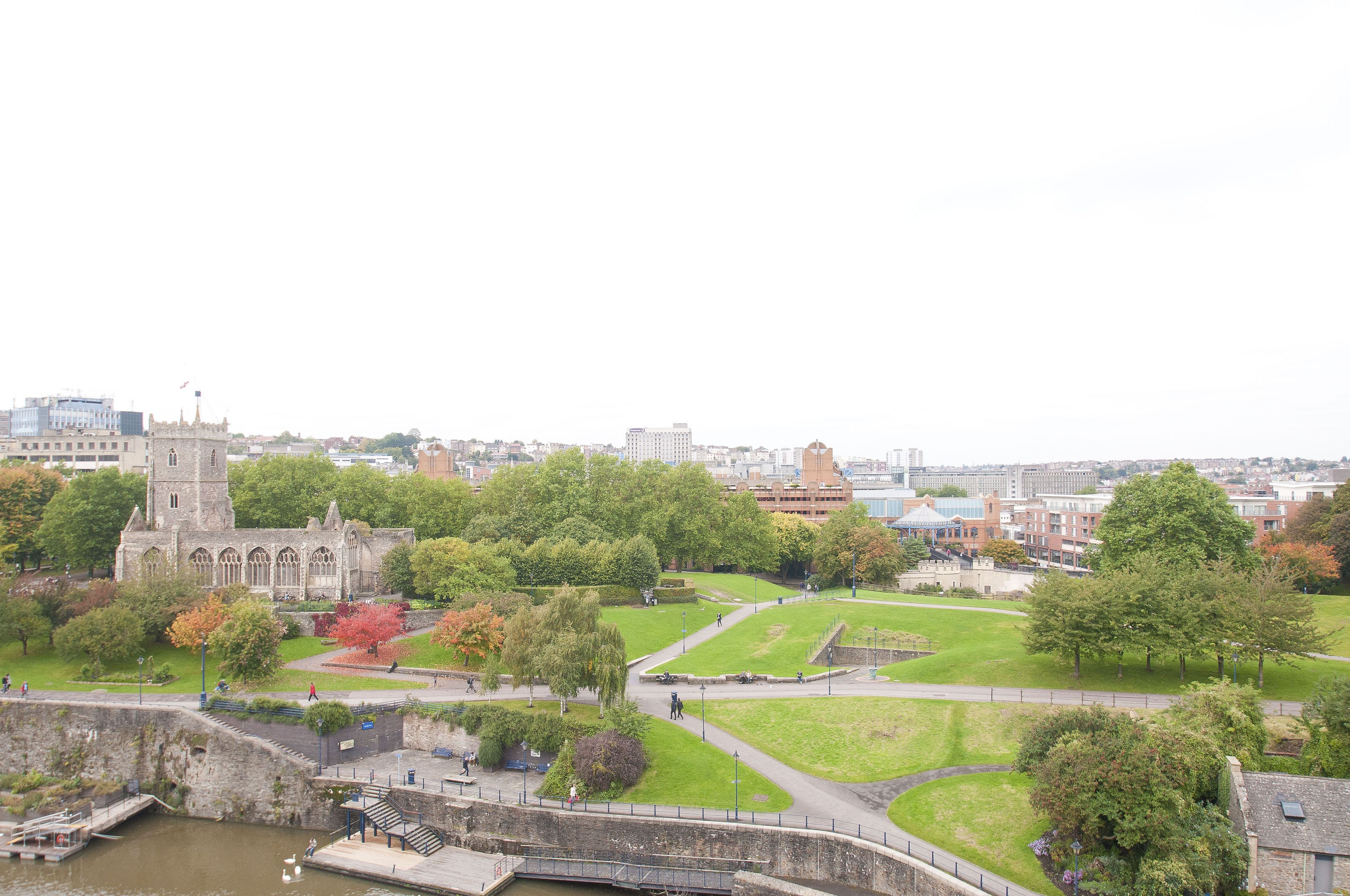 A historic building with a tower, surrounded by a park with pathways and trees.