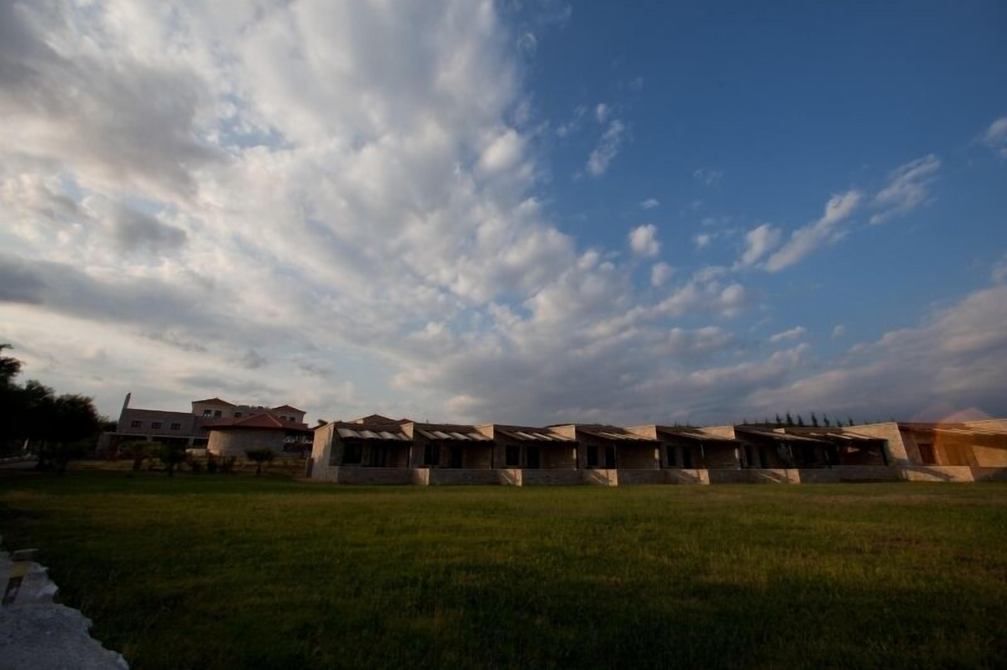 Uma fileira de edifícios modernos com telhados planos e um campo gramado em primeiro plano.