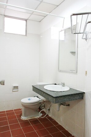 A bathroom with a white toilet, two sinks, a mirror, and a window. - JJ Guesthouse (Karon)