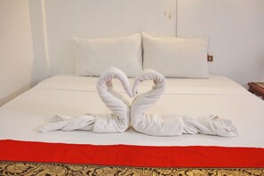A neatly made bed with white linens and a red bedspread. - JJ Guesthouse (Karon)