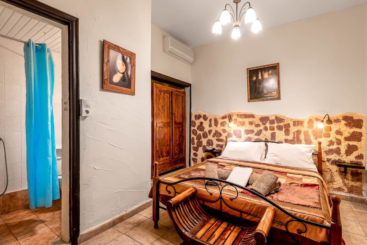Un dormitorio con una cama, cabecera de madera, aire acondicionado de pared y una puerta.