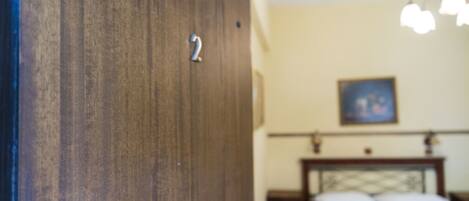 Une porte en bois portant le numéro « 2 », un lit avec une couverture et un tableau accroché au mur.