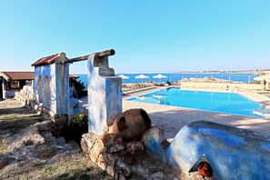 Ein Poolbereich mit einer Steinstruktur und Blick auf das Meer.