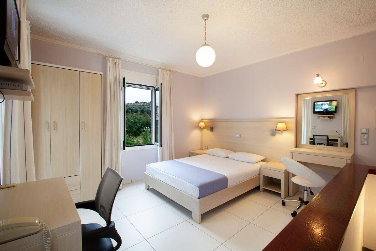 Ein Hotelzimmer mit Bett, Nachttischen, Schreibtisch, Stuhl, Fernseher und Kleiderschrank.