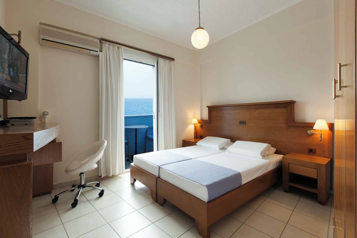 Ein Hotelzimmer mit Bett, Schreibtisch, Stuhl und Fernseher.