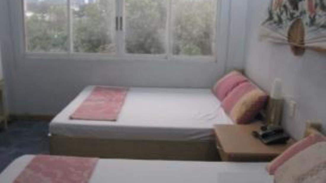 Un dormitorio con una cama individual, una mesita de noche y una ventana.