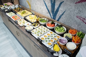 Un bufé con diversas opciones de comida, incluyendo ensaladas, frutas y salsas.