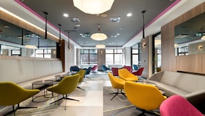 A modern waiting area with colorful chairs, a sofa, and a large geometric light fixture.