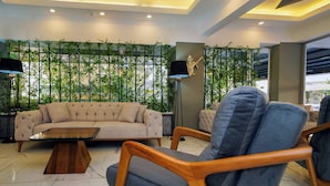A modern living room with a sofa, chairs, a coffee table, and a decorative wall with plants. - Miss Cleopatra Hotel (Alanya)