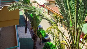 A balcony with a view of the sea, palm trees, and buildings. - Miss Cleopatra Hotel (Alanya)