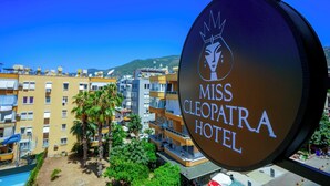 A sign for the Miss Cleopatra Hotel with a view of the surrounding buildings and palm trees. - Miss Cleopatra Hotel (Alanya)