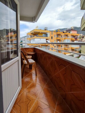 A balcony with a wooden floor and a view of yellow buildings in the background. - Miss Cleopatra Hotel (Alanya)