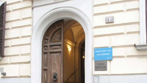 Une entrée d’immeuble avec une porte en bois, une enseigne bleue et un escalier menant à l’intérieur.