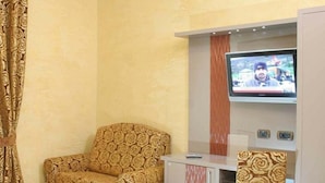 Une pièce comprenant un canapé à motifs, un téléviseur, un meuble et une chaise.