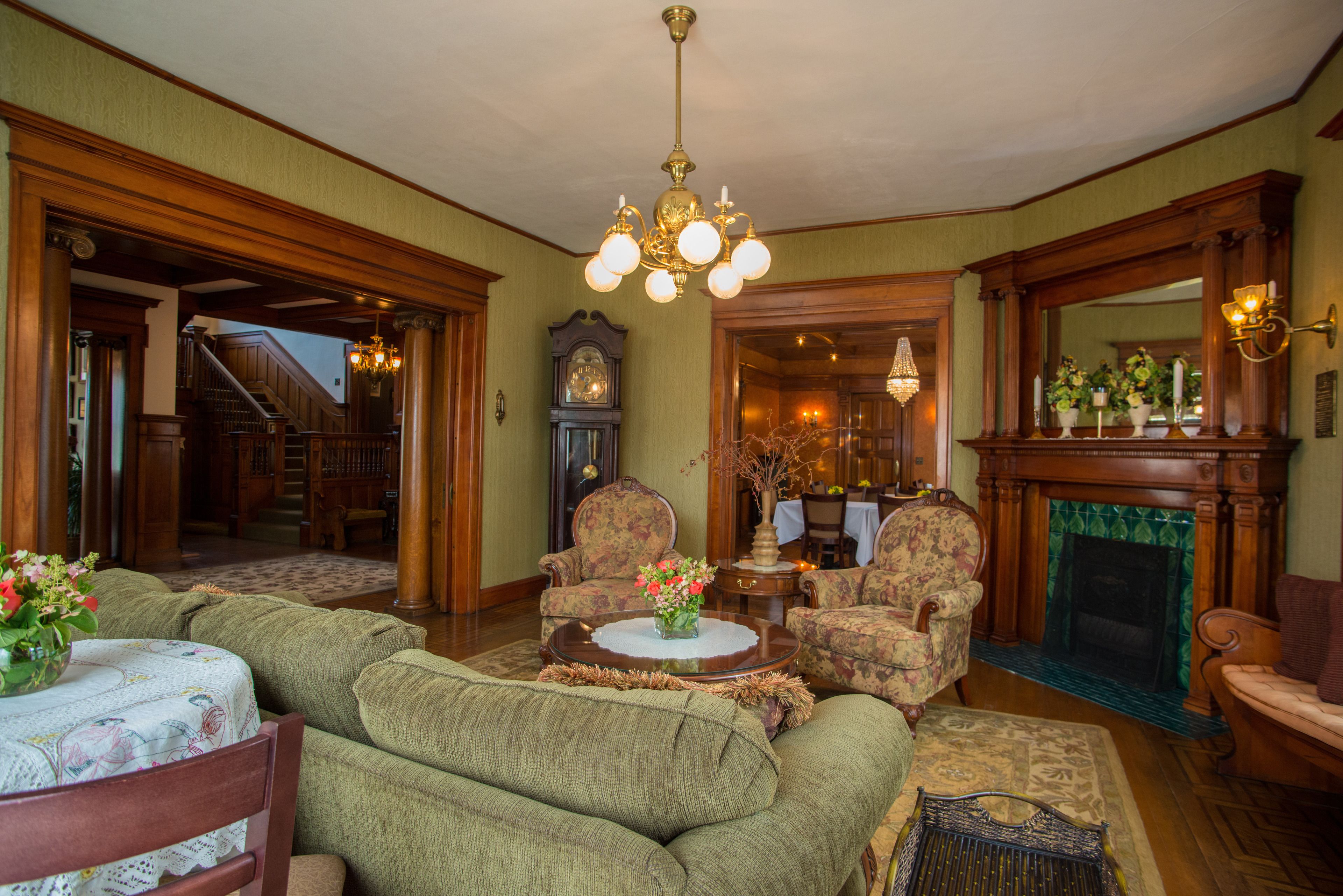 A traditional living room with a fireplace, a chandelier, and a grandfather clock.