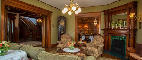 A traditional living room with a fireplace, a chandelier, and a grandfather clock.