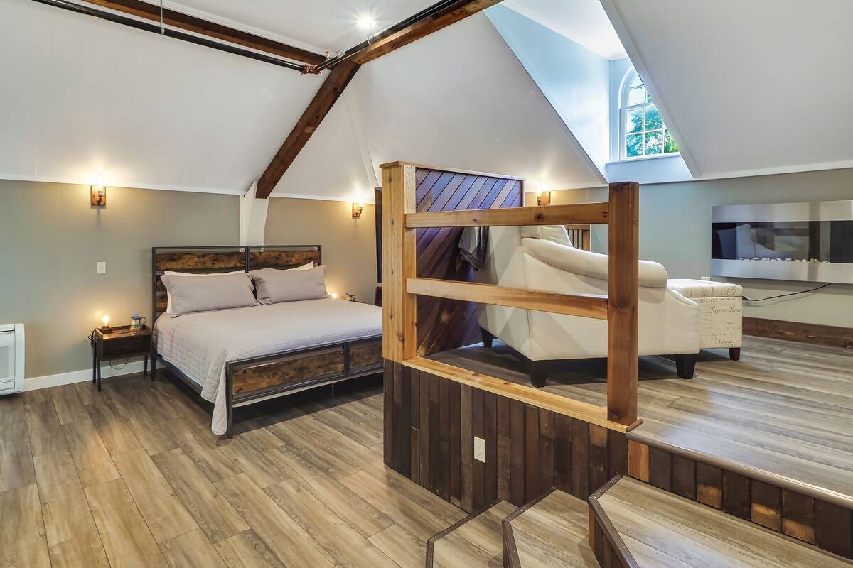 Ein Schlafzimmer mit einem hölzernen Bett, einem Nachttisch, einem Sofa und einem Fernseher.