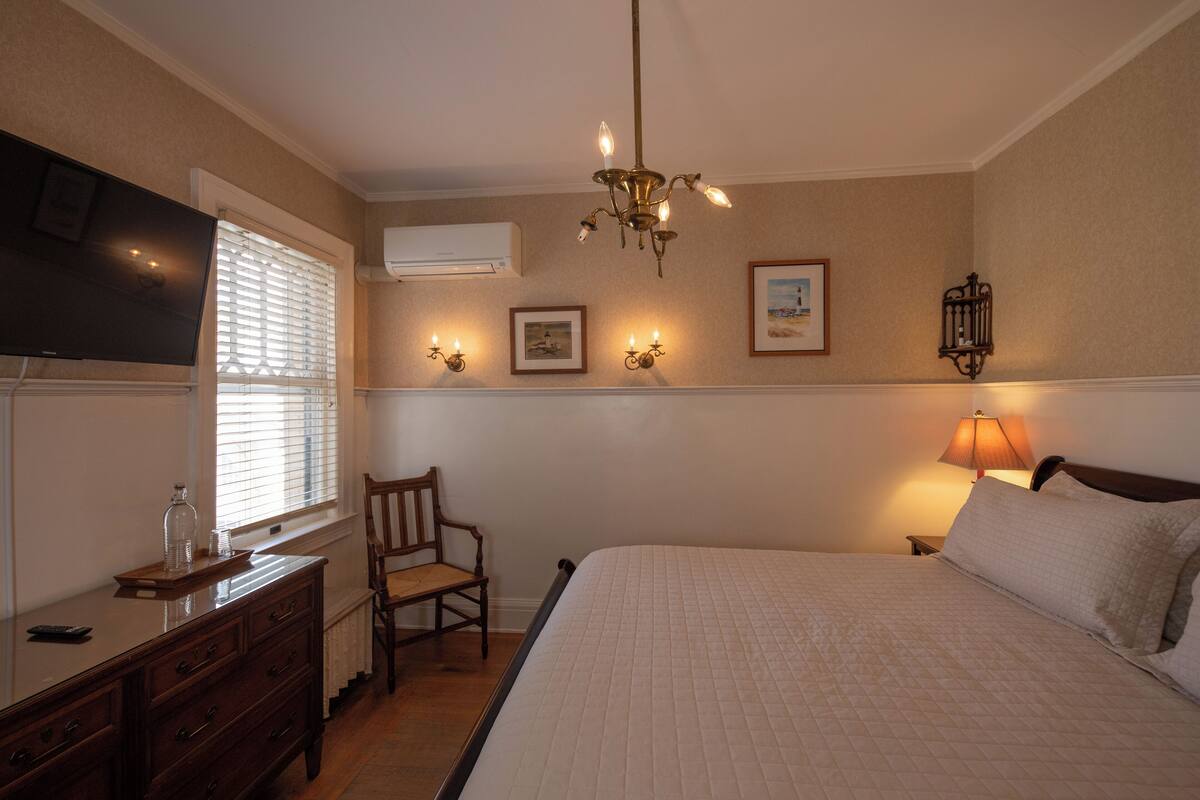 Ein Schlafzimmer mit Bett, Schminktisch, Stuhl und Fernseher.
