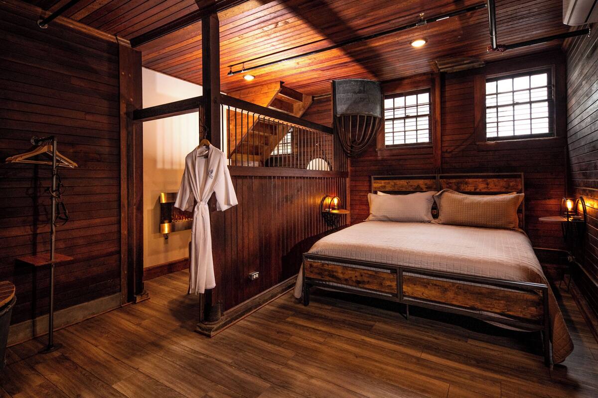 Ein schlicht eingerichtetes Schlafzimmer im Blockhausstil mit einem Bett, einer Pendelleuchte und einem Fenster.