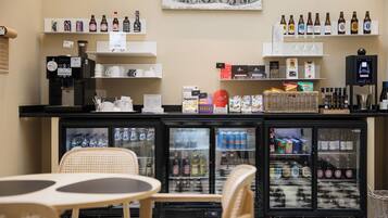 Een barruimte met flessen drank, een koffieapparaat en een koelkast vol verfrissingen.