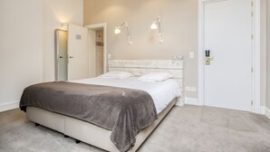Une chambre à coucher avec un lit, une porte et deux lampes fixées au mur.