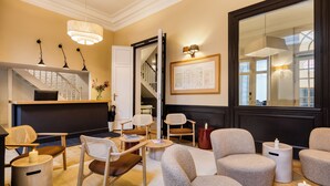 Un salon moderne avec un escalier, des sièges confortables et un grand miroir.