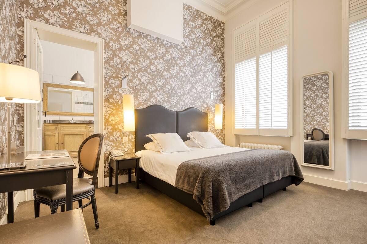 A bedroom with a bed, a desk, and a chair.